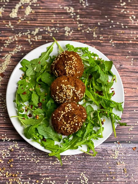 Delicious falafel on a bed of fresh arugula, sprinkled with sesame seeds, perfect for a vegetarian meal.